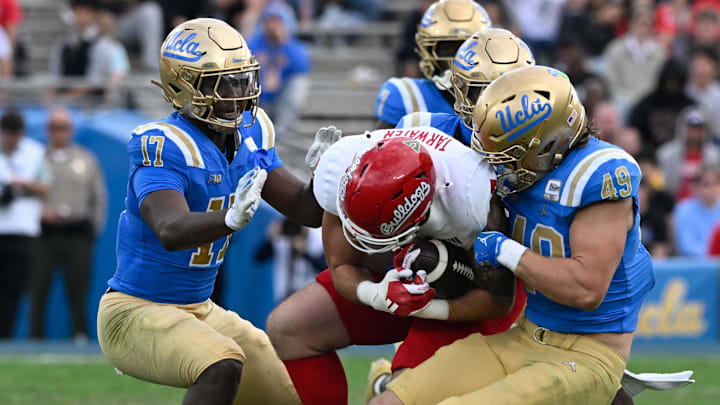Nov 30, 2024; Pasadena, California, USA; UCLA Bruins linebacker Jalen Woods (17), defensive back Jaylin Davies (6), and linebacker Carson Schwesinger (49) tackle Fresno State Bulldogs tight end Jake Tarwater (87) during the third quarter at Rose Bowl. Mandatory Credit: Robert Hanashiro-Imagn Images