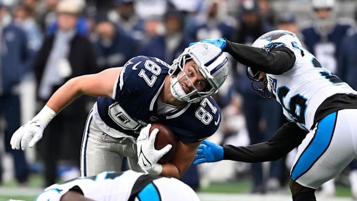 Dec 15, 2024; Charlotte, North Carolina, USA;  Dallas Cowboys tight end Jake Ferguson (87) with the ball as Carolina Panthers cornerback Chau Smith-Wade (26) defends in the second quarter at Bank of America Stadium. Mandatory Credit: Bob Donnan-Imagn Images