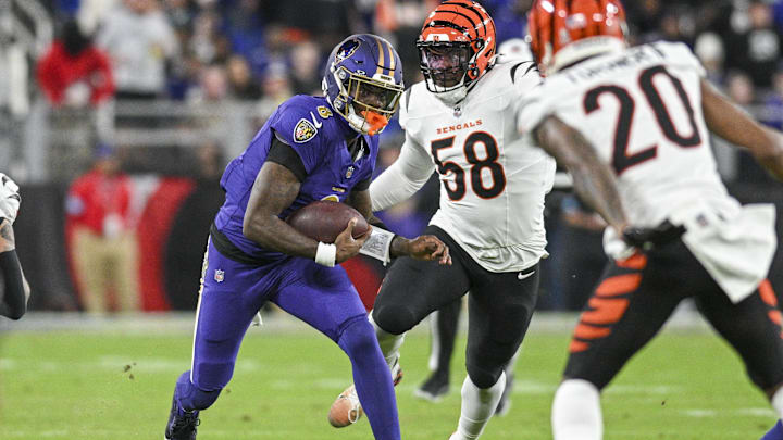 Nov 7, 2024; Baltimore, Maryland, USA;Baltimore Ravens quarterback Lamar Jackson (8) rushes  in-between Cincinnati Bengals defensive end Joseph Ossai (58) and  cornerback DJ Turner II (20)   at M&T Bank Stadium. Mandatory Credit: Tommy Gilligan-Imagn Images