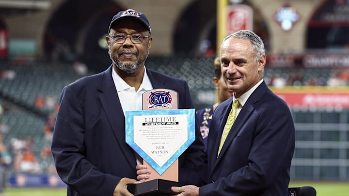 Former Houston Astros player Bob Watson holds an award wearing a suit and hat.