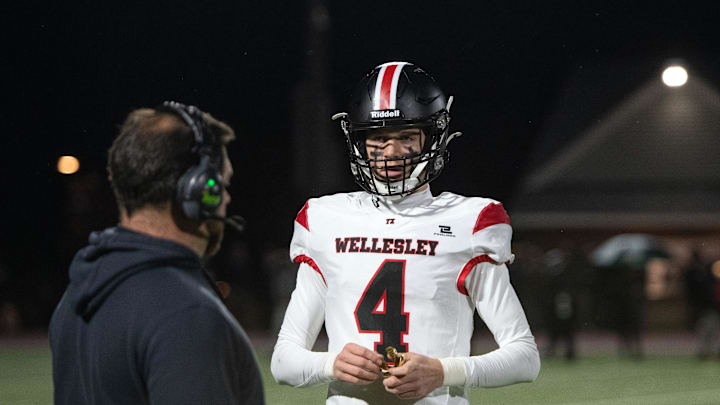 Wellesley sophomore quarterback Lukas Prock talks with a coach while running offensive plays during the Division 2 state semifinals game against Catholic Memorial at Weston High, Nov. 22, 2024. The Knights defeated the Raiders, 49-7.
