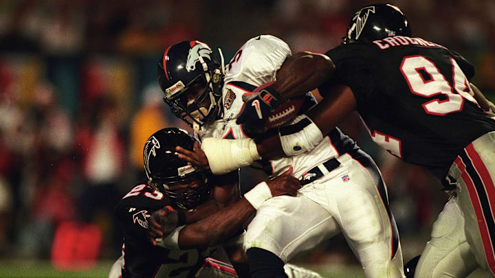 Jan 31, 1999; Miami, FL, USA; FILE PHOTO; Denver Broncos running back Terrell Davis (30) carries the ball against Atlanta Falcons defenders Ronnie Bradford (23) and Henry Crockett (94) during Super Bowl XXXIII at Dolphin Stadium. The Broncos defeated the Falcons 34-19. Mandatory Credit: RVR Photos-Imagn Images