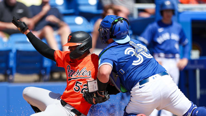 Mar 13, 2025; Dunedin, Florida, USA; Toronto Blue Jays catcher Alejandro Kirk (30) tags out Baltimore Orioles shortstop Luis Vasquez (52) in the second inning during spring training at TD Ballpark. Mandatory Credit: Nathan Ray Seebeck-Imagn Images