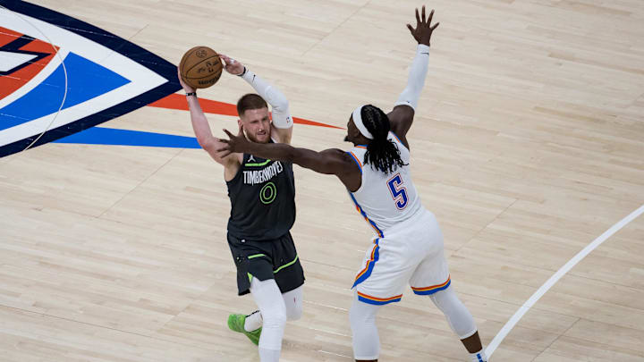 May 20, 2025; Oklahoma City, Oklahoma, USA; Minnesota Timberwolves guard Donte DiVincenzo (0) looks to pass against Oklahoma City Thunder guard Luguentz Dort (5) in the fourth quarter during game one of the western conference finals for the 2025 NBA Playoffs at Paycom Center. Mandatory Credit: Brett Rojo-Imagn Images