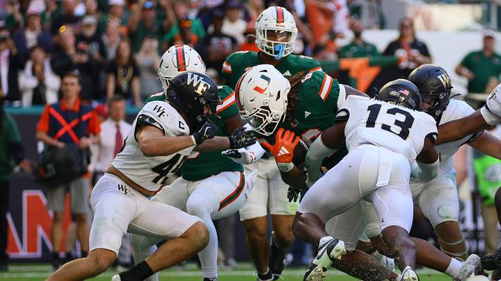 Nov 23, 2024; Miami Gardens, Florida, USA; Miami Hurricanes running back Damien Martinez (6) runs with the football as Wake Forest Demon Deacons defensive back Davaughn Patterson (13) attempts a tackle during the fourth quarter at Hard Rock Stadium. Mandatory Credit: Sam Navarro-Imagn Images