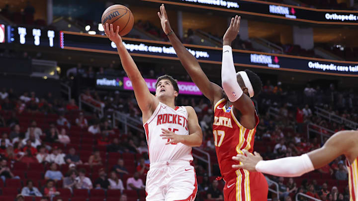 Oct 6, 2025; Houston, Texas, USA; Houston Rockets guard Reed Sheppard (15) shoots the ball as Atlanta Hawks forward/center Onyeka Okongwu (17) defends during the second quarter at Toyota Center. Mandatory Credit: Troy Taormina-Imagn Images