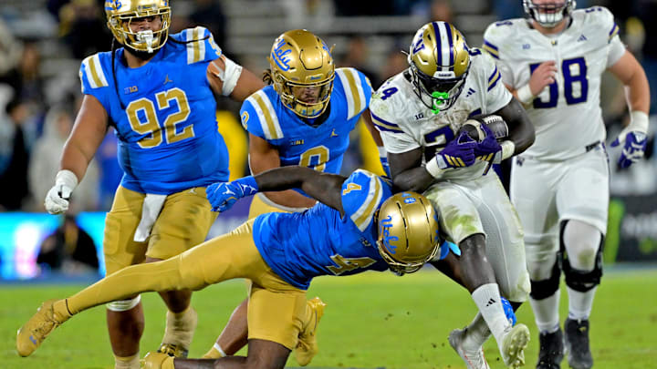 Nov 22, 2025; Pasadena, California, USA;  Washington Huskies running back Adam Mohammed (24) is stopped by UCLA Bruins defensive back Key Lawrence (4) after a gain of 15 yards and a first down during the second half at the Rose Bowl. Mandatory Credit: Jayne Kamin-Oncea-Imagn Images