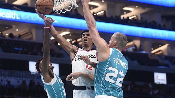 Nov 22, 2025; Charlotte, North Carolina, USA; Los Angeles Clippers guard Cam Christie (12) drives in past Charlotte Hornets guard Brandon Miller (24) and center Mason Plumlee (22) during the second half at the Spectrum Center. Mandatory Credit: Sam Sharpe-Imagn Images