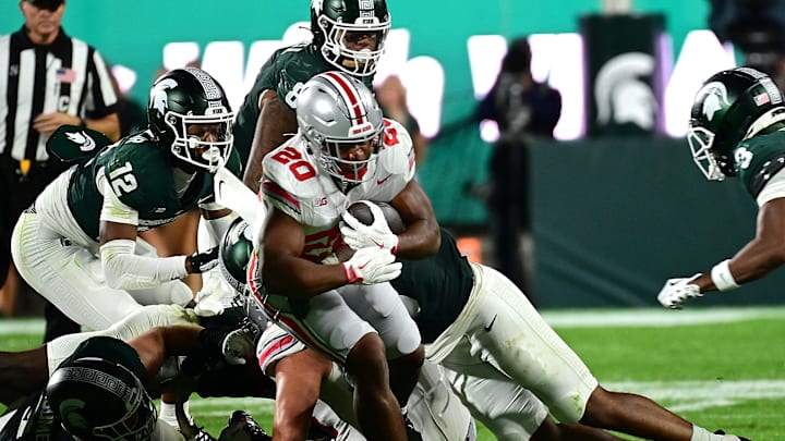 Sep 28, 2024; East Lansing, Michigan, USA;  Ohio State Buckeyes running back James Peoples (20) struggles for a first down against the Michigan State Spartans in the fourth quarter at Spartan Stadium. Mandatory Credit: Dale Young-Imagn Images