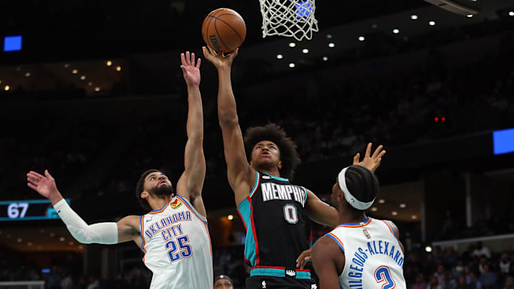 Nov 9, 2025; Memphis, Tennessee, USA; Memphis Grizzlies forward Jaylen Wells (0) shoots as Oklahoma City Thunder guards Ajay Mitchell (25) and Shai Gilgeous-Alexander (2) defend during the third quarter at FedExForum. Mandatory Credit: Petre Thomas-Imagn Images