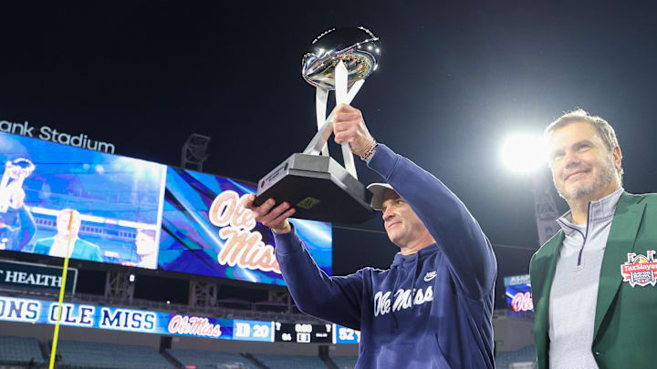 Jan 2, 2025; Jacksonville, FL, USA; Mississippi Rebels head coach Lane Kiffin is givent the Gator Bowl trophy after beating the Duke Blue Devils at EverBank Stadium. Mandatory Credit: Nathan Ray Seebeck-Imagn Images Jan 2, 2025; Jacksonville, FL, USA; Mississippi Rebels head coach Lane Kiffin is givent the Gator Bowl trophy after beating the Duke Blue Devils at EverBank Stadium. Mandatory Credit: Nathan Ray Seebeck-Imagn Images
