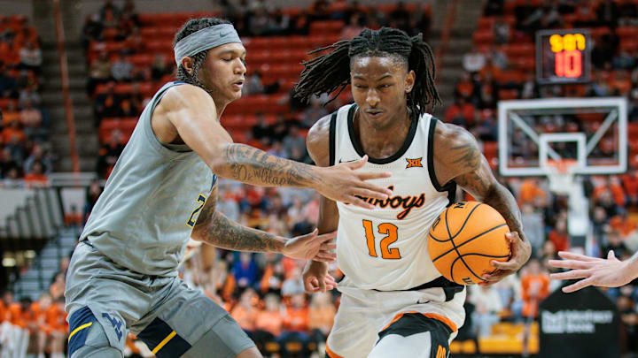 Jan 27, 2024; Stillwater, Oklahoma, USA; Oklahoma State Cowboys guard Javon Small (12) drives around West Virginia Mountaineers guard RaeQuan Battle (21) during the first half at Gallagher-Iba Arena. Mandatory Credit: William Purnell-Imagn Images