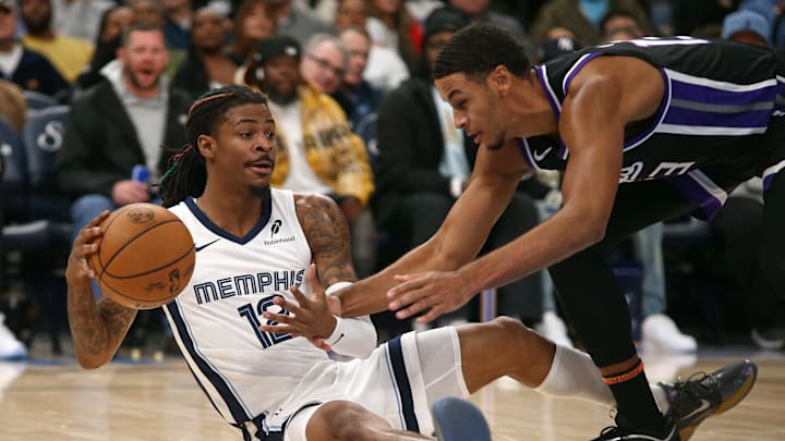 Dec 5, 2024; Memphis, Tennessee, USA; Memphis Grizzlies guard Ja Morant (12) collects a loose ball over Sacramento Kings forward Keegan Murray (13) during the first quarter at FedExForum. Mandatory Credit: Petre Thomas-Imagn Images