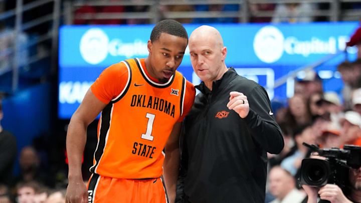 Feb 22, 2025; Lawrence, Kansas, USA; Oklahoma State Cowboys guard Bryce Thompson (1) talks with head coach Steve Lutz against the Kansas Jayhawks during the first half at Allen Fieldhouse. Mandatory Credit: Denny Medley-Imagn Images Feb 22, 2025; Lawrence, Kansas, USA; Oklahoma State Cowboys guard Bryce Thompson (1) talks with head coach Steve Lutz against the Kansas Jayhawks during the first half at Allen Fieldhouse. Mandatory Credit: Denny Medley-Imagn Images