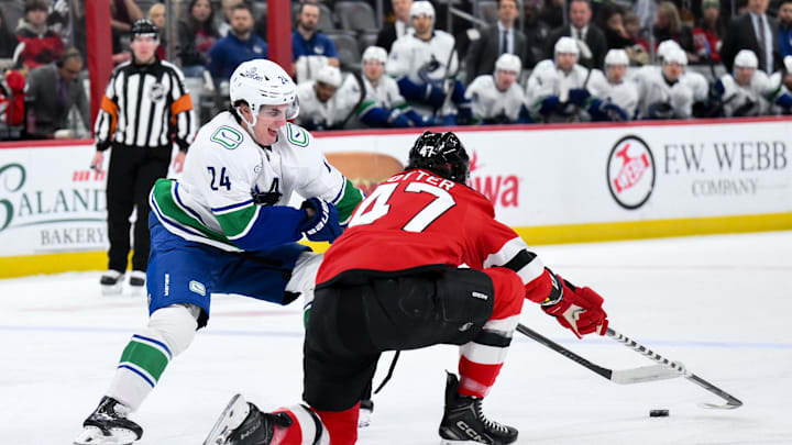 Dec 14, 2025; Newark, New Jersey, USA; Vancouver Canucks defenseman Zeev Buium (24) skates with the puck while defended by New Jersey Devils left wing Paul Cotter (47) during the first period at Prudential Center. Mandatory Credit: John Jones-Imagn Images Dec 14, 2025; Newark, New Jersey, USA; Vancouver Canucks defenseman Zeev Buium (24) skates with the puck while defended by New Jersey Devils left wing Paul Cotter (47) during the first period at Prudential Center. Mandatory Credit: John Jones-Imagn Images