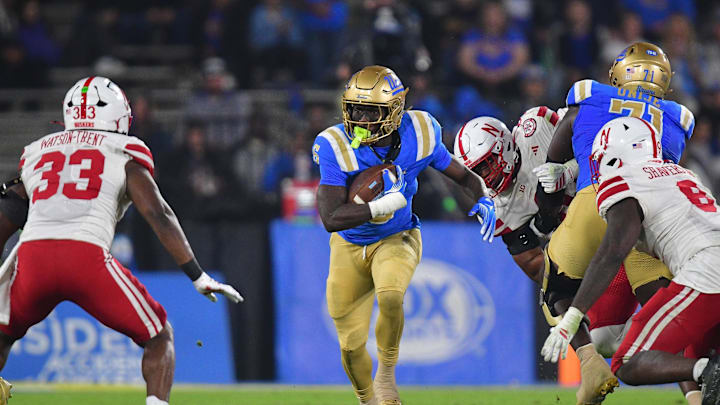 Nov 8, 2025; Pasadena, California, USA; UCLA Bruins running back Anthony Woods (6) runs the ball against Nebraska Cornhuskers linebacker Marques Watson-Trent (33) during the first half at the Rose Bowl. Mandatory Credit: Gary A. Vasquez-Imagn Images