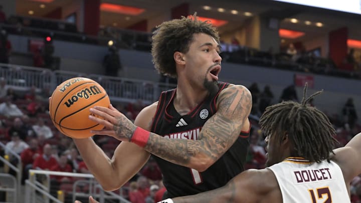 Nov 22, 2024; Louisville, Kentucky, USA;  Louisville Cardinals guard J'Vonne Hadley (1) looks to pass over Winthrop Eagles forward K.J. Doucet (12) during the second half at KFC Yum! Center. Louisville defeated Winthrop 76-61.Mandatory Credit: Jamie Rhodes-Imagn Images