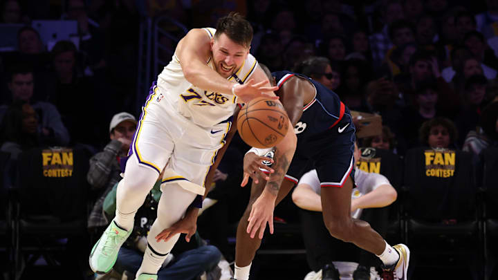 Los Angeles Lakers guard Luka Doncic (77) and LA Clippers guard Kris Dunn (8) chase a loose ball during the first quarter at Crypto.com Arena.