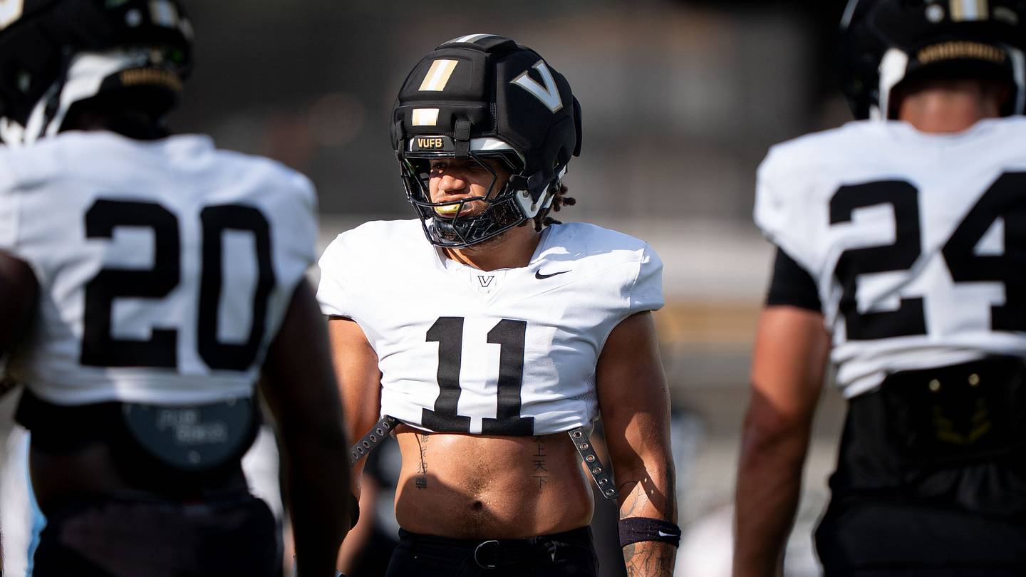 Un gruppo di linebacker di Vanderbilt durante un allenamento, con un allenatore che parla con un scout NFL