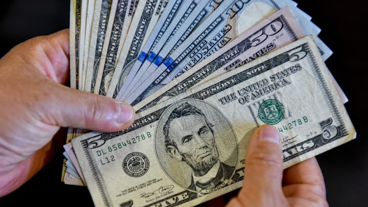 In this photo illustration, a person is seen holding 100, 50...