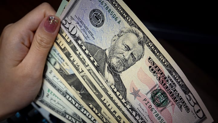 In this photo illustration, a person holds 1, 10, 20, and 50...