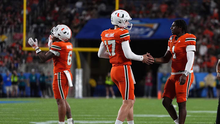 Dec 28, 2024; Orlando, FL, USA; Miami Hurricanes quarterback Emory Williams (17) shakes hands with quarterback Cam Ward (1) after a touchdown against the Iowa State Cyclones during the second half at Camping World Stadium. Mandatory Credit: Jasen Vinlove-Imagn Images