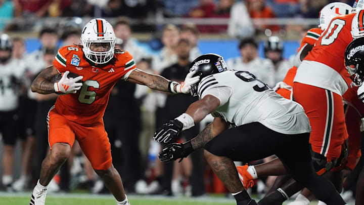 Dec 28, 2024; Orlando, FL, USA; Miami Hurricanes running back Damien Martinez (6) stiff arms Iowa State Cyclones linebacker Cael Brezina (9) during the second half at Camping World Stadium. Mandatory Credit: Jasen Vinlove-Imagn Images