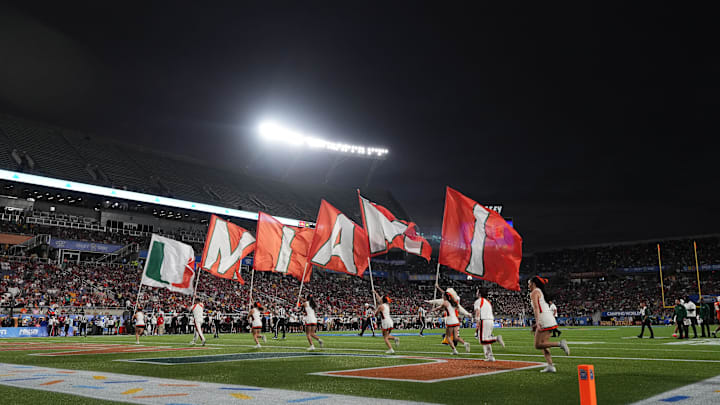 Dec 28, 2024; Orlando, FL, USA; Miami Hurricanes cheerleaders run on the field with flags after a touchdown against the Iowa State Cyclones during the second half at Camping World Stadium. Mandatory Credit: Jasen Vinlove-Imagn Images