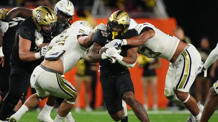 Dec 22, 2023; Tampa, FL, USA; UCF Knights running back RJ Harvey (7) runs the ball between Georgia Tech Yellow Jackets linebacker Kyle Efford (44) and inebacker Paul Moala (13) during the first half of the Gasparilla Bowl at Raymond James Stadium. Mandatory Credit: Jasen Vinlove-USA TODAY Sports