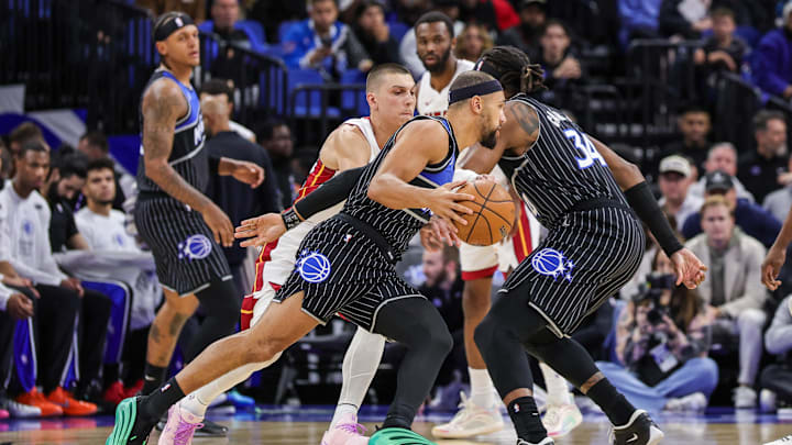 Dec 9, 2025; Orlando, Florida, USA; Orlando Magic guard Jalen Suggs (4) drives past Miami Heat guard Tyler Herro (14) during the first quarter at Kia Center. Mandatory Credit: Mike Watters-Imagn Images