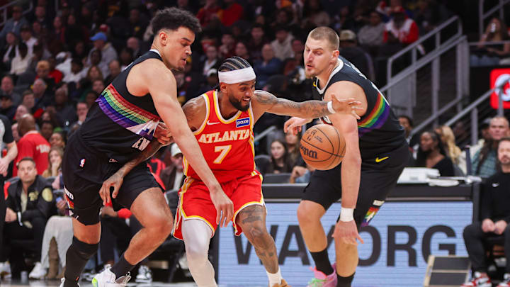Dec 5, 2025; Atlanta, Georgia, USA; Atlanta Hawks guard Nickeil Alexander-Walker (7) is defended by Denver Nuggets forward Spencer Jones (21) and center Nikola Jokic (15) in the second quarter at State Farm Arena. Mandatory Credit: Brett Davis-Imagn Images

