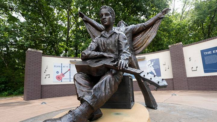 The statue “Becoming,” which depicts a young Elvis Presley with a guitar on his lap and the adult, famous Elvis Presley standing behind him at the Elvis Presley Birthplace in Tupelo, Miss. The statue “Becoming,” which depicts a young Elvis Presley with a guitar on his lap and the adult, famous Elvis Presley standing behind him at the Elvis Presley Birthplace in Tupelo, Miss.
