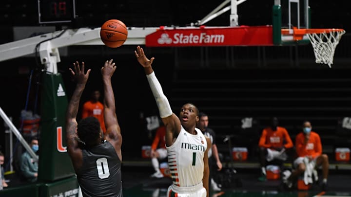 Dec 19, 2020; Coral Gables, Florida, USA; Jacksonville Dolphins forward Dontarius James (0) shoots the ball over Miami Hurricanes forward Anthony Walker (1) during the first half at Watsco Center. Mandatory Credit: Jasen Vinlove-Imagn Images