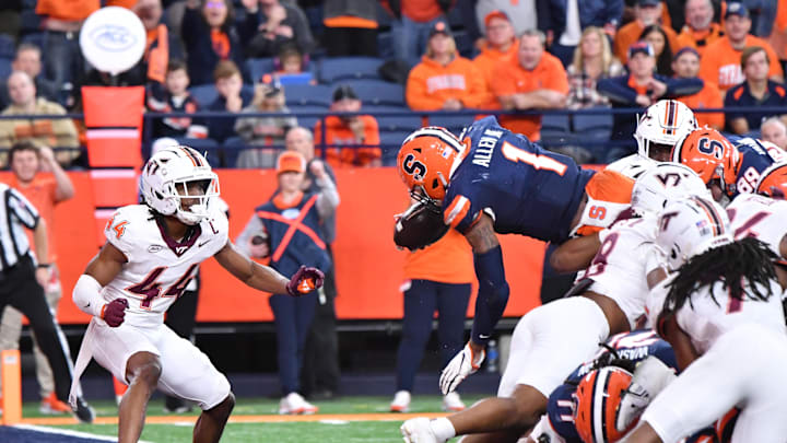 Nov 2, 2024; Syracuse, New York, USA; Syracuse Orange running back LeQuint Allen (1) leaps into the endzone to score a tying touchdown as Virginia Tech Hokies cornerback Dorian Strong (44) looks on in the fourth quarter at JMA Wireless Dome. Mandatory Credit: Mark Konezny-Imagn Images