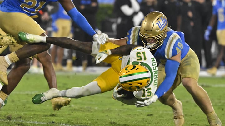 Sep 28, 2024; Pasadena, California, USA; Oregon Ducks wide receiver Tez Johnson (15) is sent flying through the air as UCLA Bruins linebacker Carson Schwesinger (49) makes the tackle in the fourth quarter at Rose Bowl. Mandatory Credit: Robert Hanashiro-Imagn Images