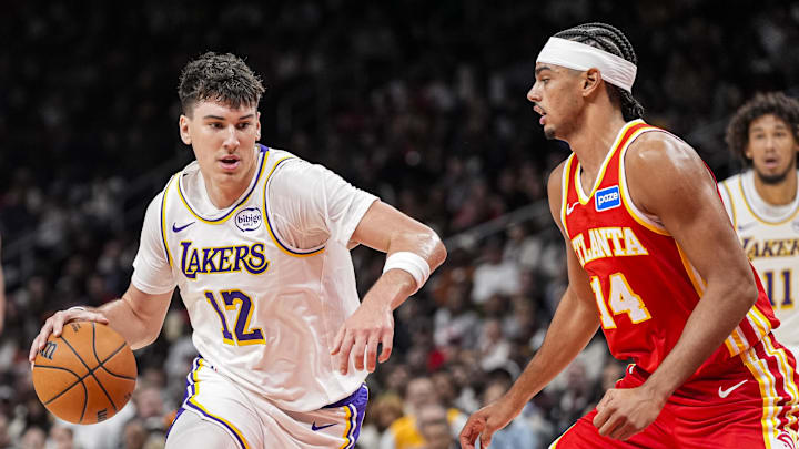 Nov 8, 2025; Atlanta, Georgia, USA; Los Angeles Lakers forward Jake LaRavia (12) dribbles against Atlanta Hawks forward Asa Newell (14) during the first half at State Farm Arena. Mandatory Credit: Dale Zanine-Imagn Images
