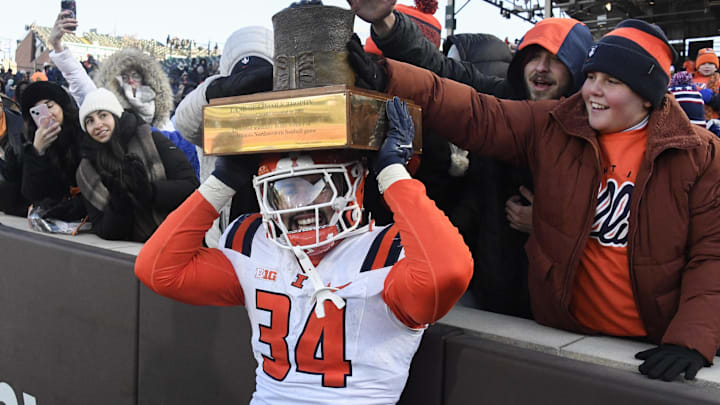 Nov 30, 2024; Chicago, Illinois, USA;  Illinois Fighting Illini linebacker Ryan Meed (34) holds the “Land of Lincoln” trophy after a game against the Northwestern Wildcats at Wrigley Field. Mandatory Credit: Matt Marton-Imagn Images