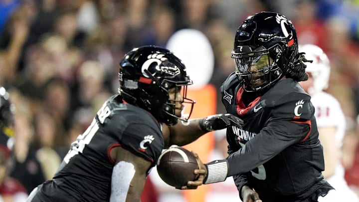 Cincinnati Bearcats quarterback Emory Jones hands the ball to running back Corey Kiner