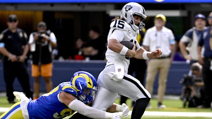 Oct 20, 2024; Inglewood, California, USA; Los Angeles Rams linebacker Michael Hoecht (left) stops Las Vegas Raiders quarterback Gardner Minshew (15) in the first half at SoFi Stadium. Mandatory Credit: Alex Gallardo-Imagn Images