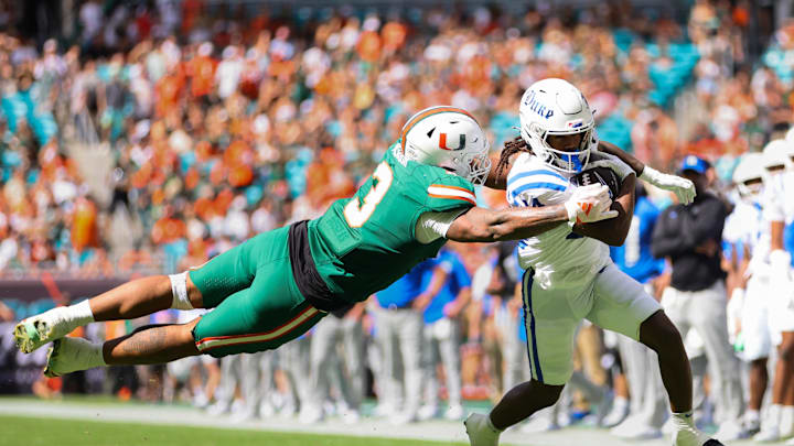 Nov 2, 2024; Miami Gardens, Florida, USA; Duke Blue Devils wide receiver Que'Sean Brown (14) runs with the football past Miami Hurricanes defensive lineman Akheem Mesidor (3) during the second quarter at Hard Rock Stadium. Mandatory Credit: Sam Navarro-Imagn Images