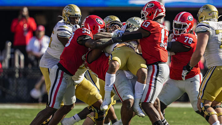 Nov 26, 2022; Athens, Georgia, USA; Georgia Tech Yellow Jackets running back Dontae Smith (4) is lifted in the air as he is tackled by Georgia Bulldogs linebacker Robert Beal Jr. (33) and defensive linemen Jalen Carter (88) and Mykel Williams (13) during the first half at Sanford Stadium. Mandatory Credit: Dale Zanine-Imagn Images Nov 26, 2022; Athens, Georgia, USA; Georgia Tech Yellow Jackets running back Dontae Smith (4) is lifted in the air as he is tackled by Georgia Bulldogs linebacker Robert Beal Jr. (33) and defensive linemen Jalen Carter (88) and Mykel Williams (13) during the first half at Sanford Stadium. Mandatory Credit: Dale Zanine-Imagn Images