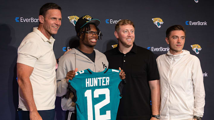 Apr 25, 2025; Jacksonville, FL, USA; Jacksonville Jaguars first round draft pick Travis Hunter poses for a photo with executive vice president of football operations Tony Boselli, head coach Liam Coen, and general manager James Gladstone, during a press conference at Miller Electric Center. Mandatory Credit: Travis Register-Imagn Images Apr 25, 2025; Jacksonville, FL, USA; Jacksonville Jaguars first round draft pick Travis Hunter poses for a photo with executive vice president of football operations Tony Boselli, head coach Liam Coen, and general manager James Gladstone, during a press conference at Miller Electric Center. Mandatory Credit: Travis Register-Imagn Images