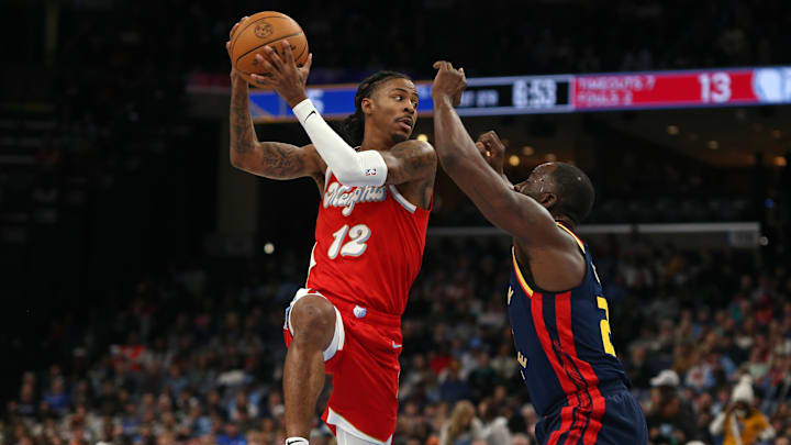Dec 19, 2024; Memphis, Tennessee, USA; Memphis Grizzlies guard Ja Morant (12) passes the ball as Golden State Warriors forward Draymond Green (23) defends during the first quarter at FedExForum. Mandatory Credit: Petre Thomas-Imagn Images