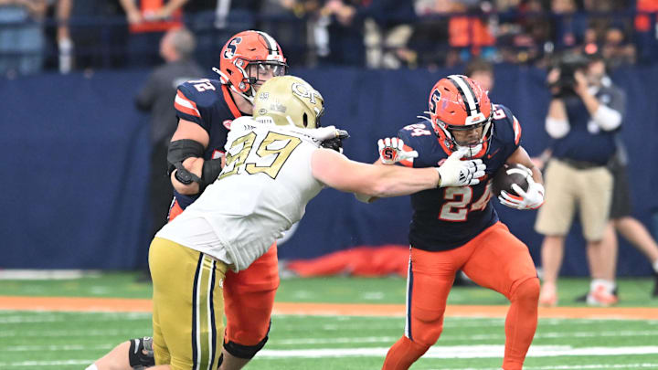 Sep 7, 2024; Syracuse, New York, USA; Syracuse Orange running back Will Nixon (24) avoids a tackle by Georgia Tech Yellow Jackets defensive lineman Jordan van den Berg (99) in the third quarter at the JMA Wireless Dome. Mandatory Credit: Mark Konezny-Imagn Images