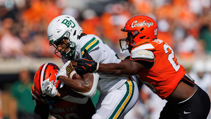 Sep 27, 2025; Stillwater, Oklahoma, USA; Baylor Bears wide receiver Josh Cameron (34) is tackled by Oklahoma State Cowboys linebacker Ike Esonwune (25) during the first half at Boone Pickens Stadium. Mandatory Credit: William Purnell-Imagn Images