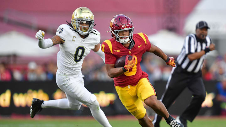 Nov 30, 2024; Los Angeles, California, USA; Southern California Trojans running back Quinten Joyner (0) runs the ball ahead of Notre Dame Fighting Irish safety Xavier Watts (0) during the second half at the Los Angeles Memorial Coliseum. Mandatory Credit: Gary A. Vasquez-Imagn Images