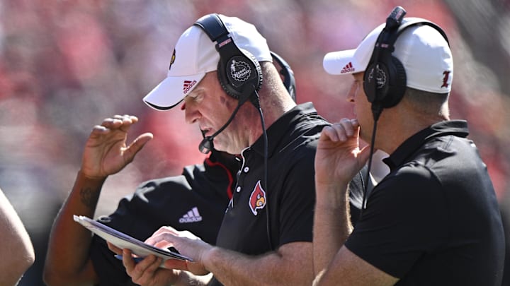 Oct 5, 2024; Louisville, Kentucky, USA;  Louisville Cardinals head coach Jeff Brohm looks through his play book during the second half against the Southern Methodist Mustangs at L&N Federal Credit Union Stadium. Mandatory Credit: Jamie Rhodes-Imagn Images