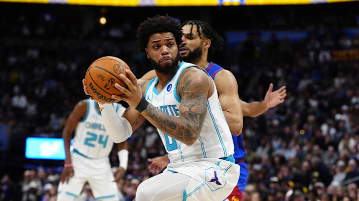 Jan 18, 2026; Denver, Colorado, USA; Charlotte Hornets forward Miles Bridges (0) drives around Denver Nuggets guard Jamal Murray (27) in the first quarter at Ball Arena. Mandatory Credit: Ron Chenoy-Imagn Images