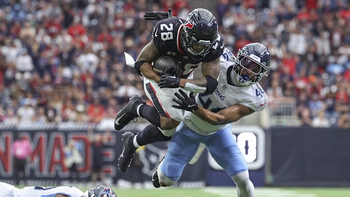 Nov 24, 2024; Houston, Texas, USA; Houston Texans running back Joe Mixon (28) runs with the ball as Tennessee Titans safety Mike Brown (44) attempts to make a tackle during the fourth quarter at NRG Stadium. Mandatory Credit: Troy Taormina-Imagn Images