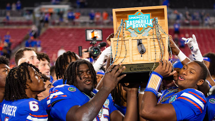 Florida Gators defensive lineman D'Antre Robinson (35) and Florida Gators quarterback DJ Lagway (2) lifts the 2024 Union Home Mortgage Gasparilla Bowl trophyat Raymond James Stadium in Tampa, FL on Friday, December 20, 2024 after defeating Tulane 33-8. [Doug Engle/Gainesville Sun]